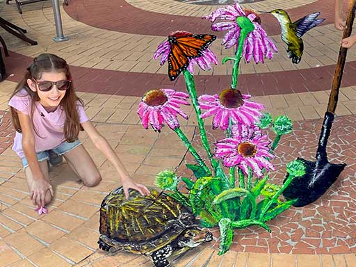 3D chalk art of digging garden flowers with turtle, hummingbird and butterfly.