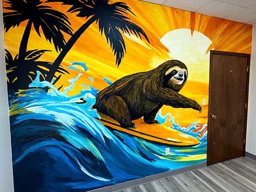 Angle view of wall mural featuring a sloth surfing on a surfboard against a bright tropical sunset background