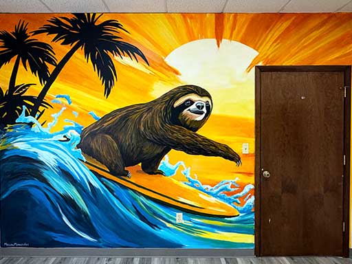 Wall mural featuring a sloth surfing on a surfboard against a bright tropical sunset background