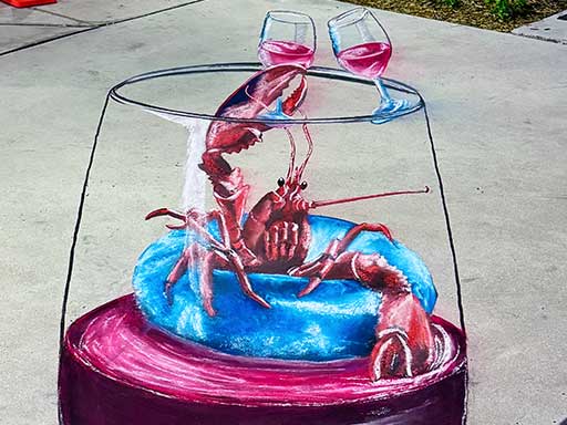 Chalk art of lobster floating on pool floatie inside a wine glass