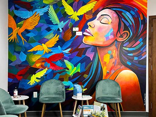Colorful abstract wall mural with woman's profile and birds, furnished office